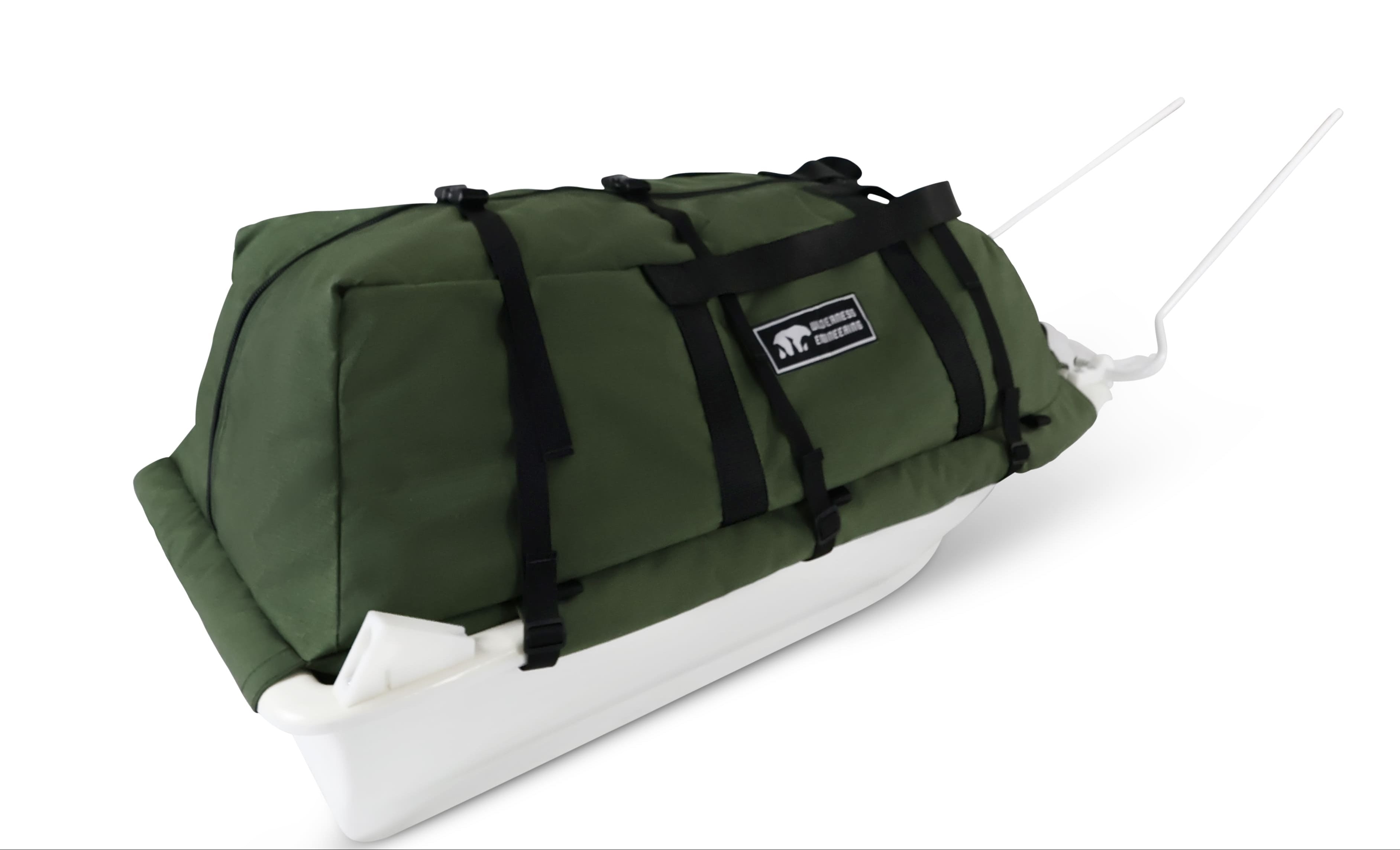 A Olive Green snowmobile Sled Pulk cargo bag with black straps and a white plastic base, shown on a white studio background. With a tag labeled 'Wilderness Engineering'.