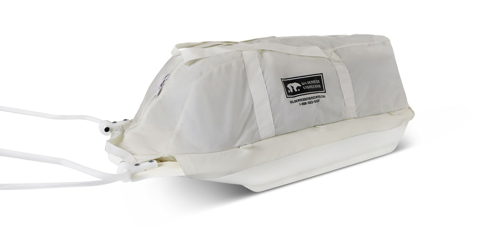 A white snowmobile Sled Pulk cargo bag with black straps and a white plastic base, shown on a white studio background. With a tag labeled 'Wilderness Engineering'.